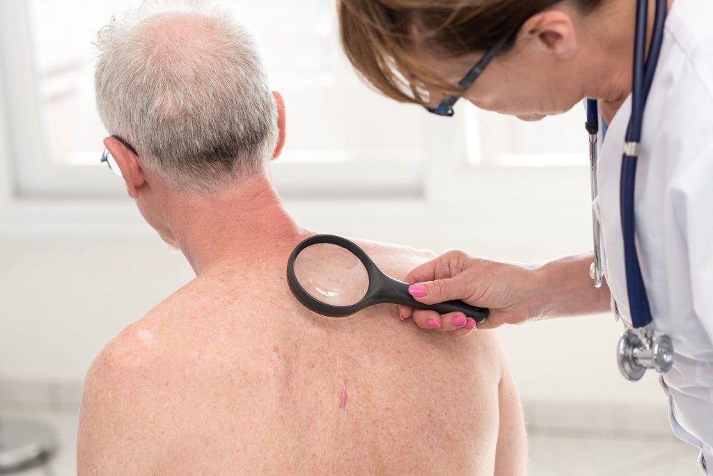 doctor examining back of old man