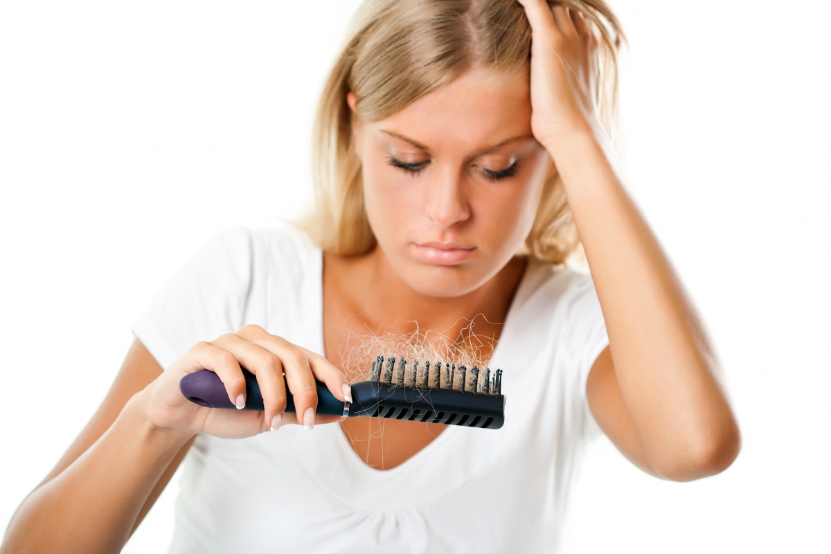 woman looking at hair on her brush