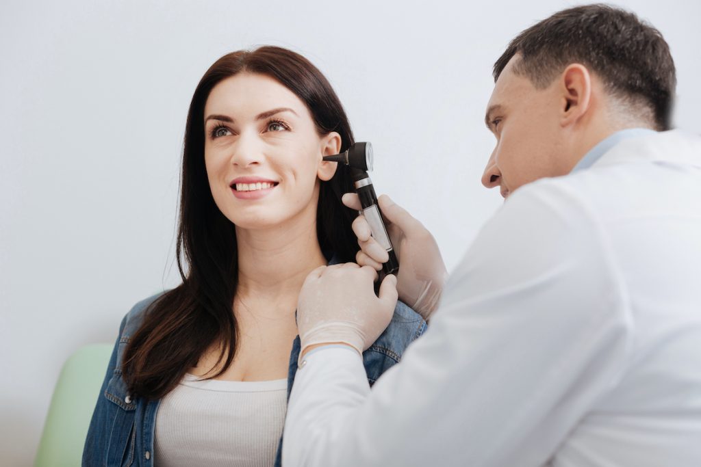 doctor checking woman's ears