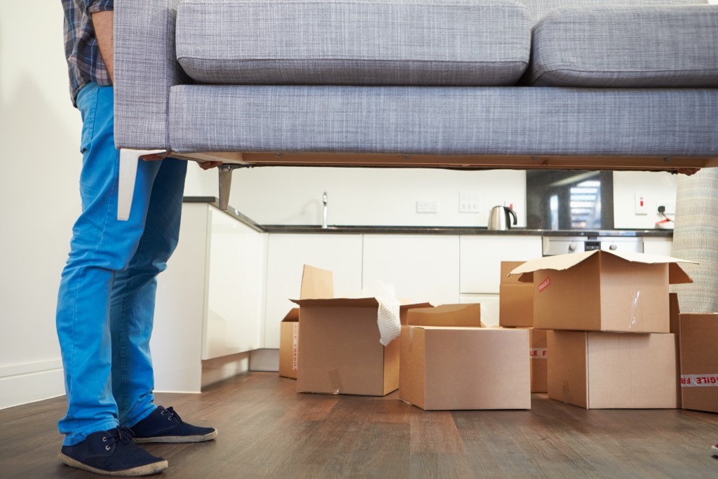 Close Up Of Man Carrying Sofa As He Moves Into New Home