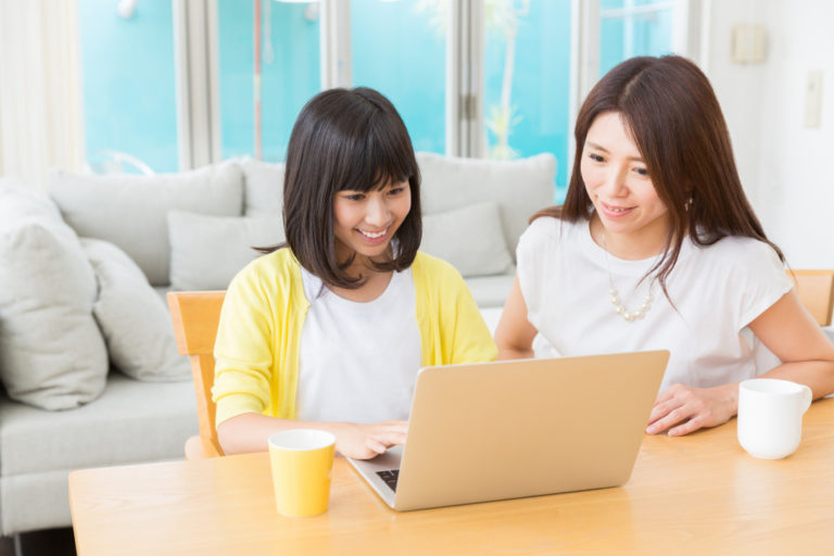 Mom and teenaged daughter looking at laptop