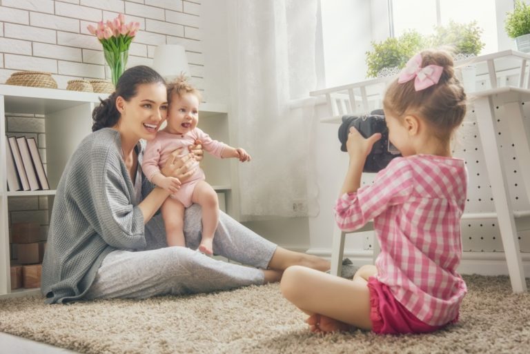 toddler taking a picture of mother and baby