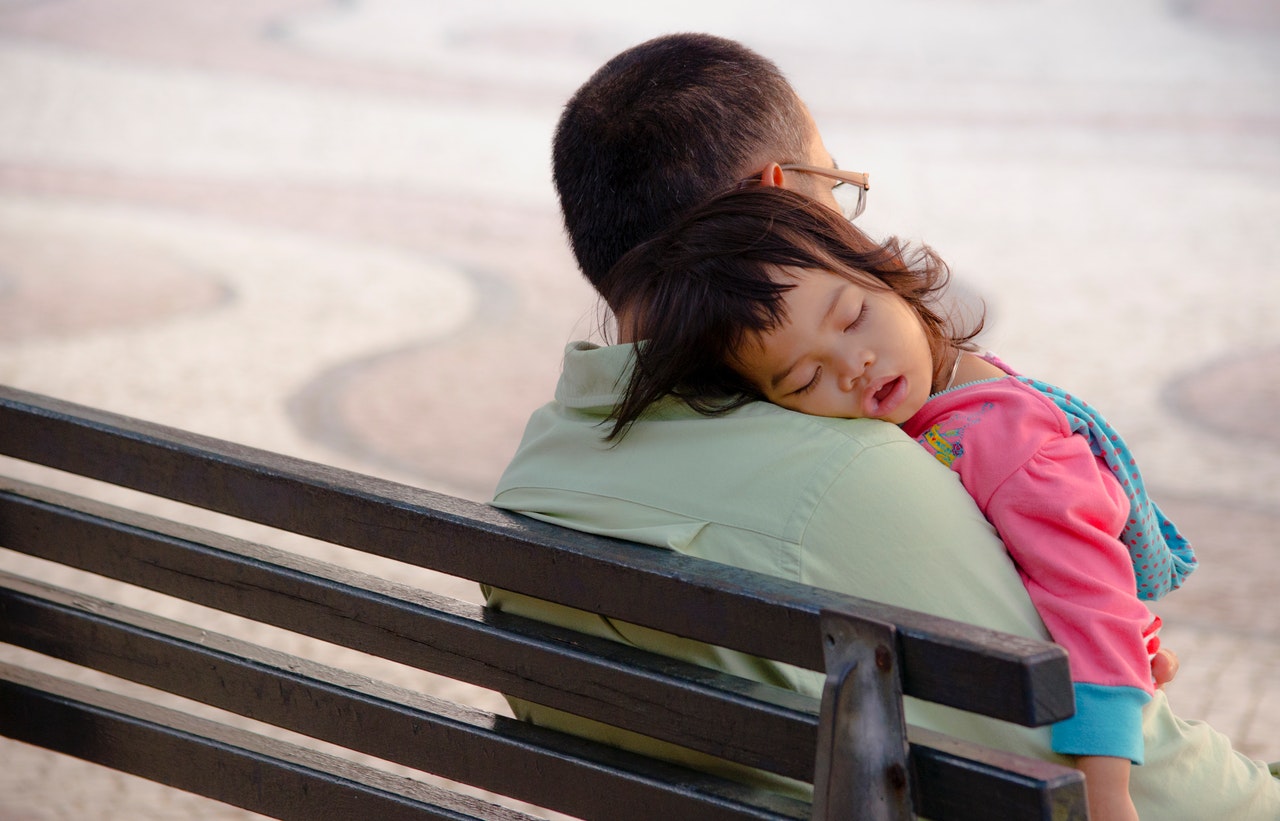 young girl sleeping on father's shoulder