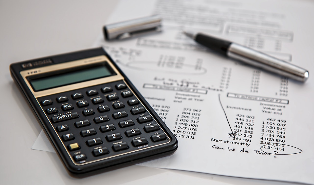 a calculator a pen and a sheet of paper on a desk