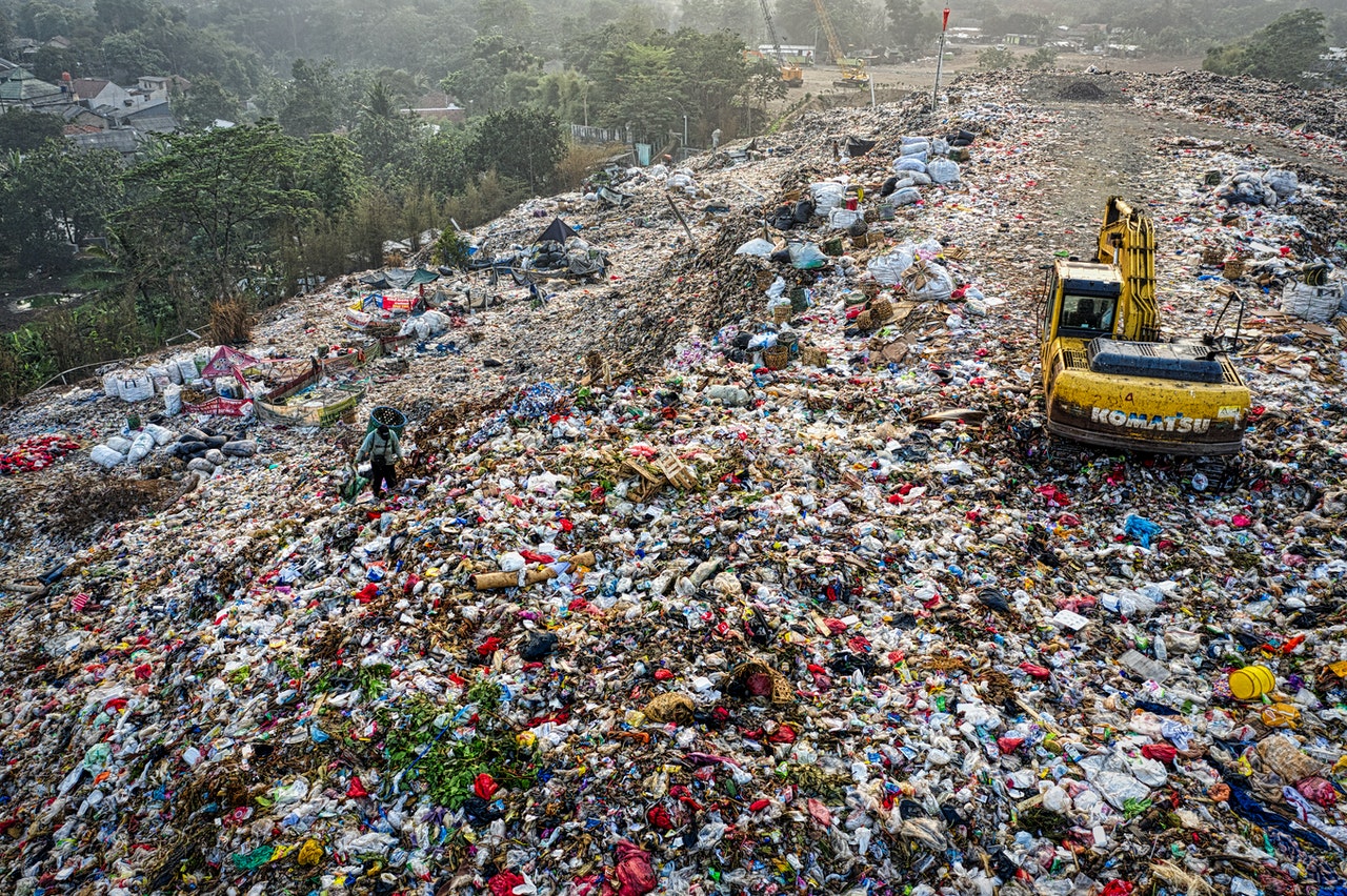 an excavator in a mountain of garbage