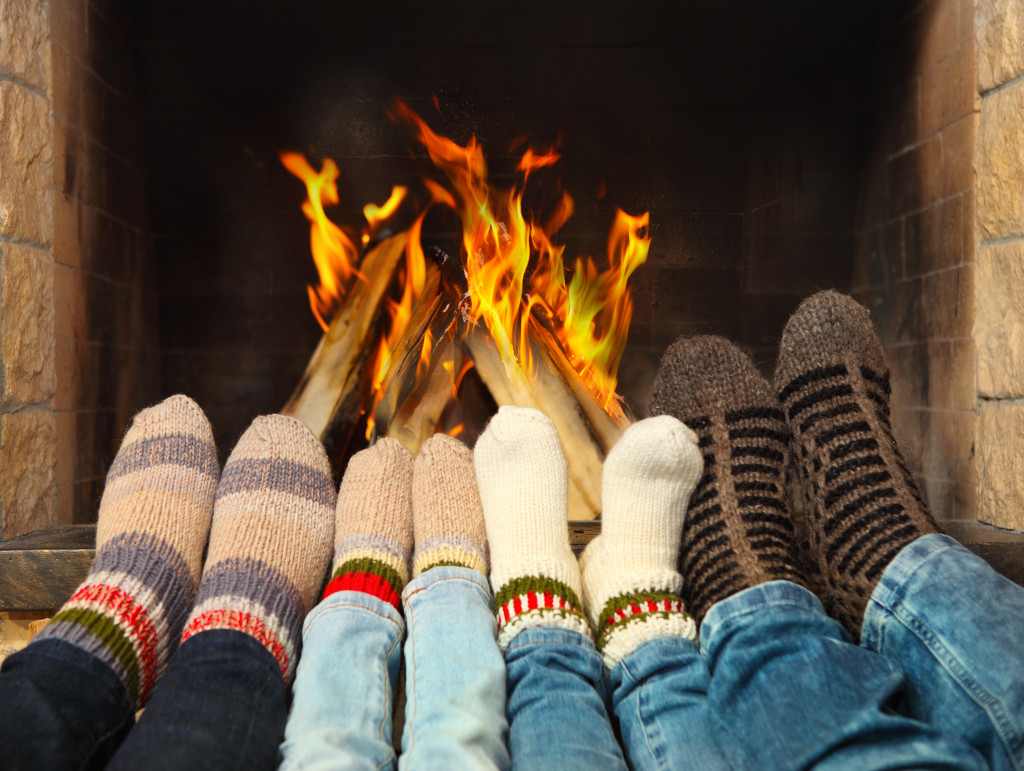 four pairs of feet in front of a fireplace