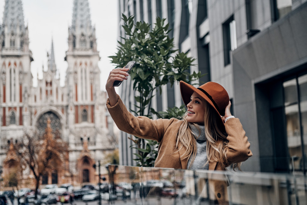 Fashionable woman taking selfie wearing red hat on her phone