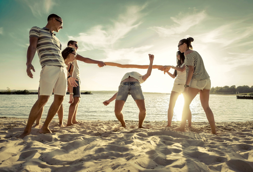 A group of friends having fun while playing limbo on the beach