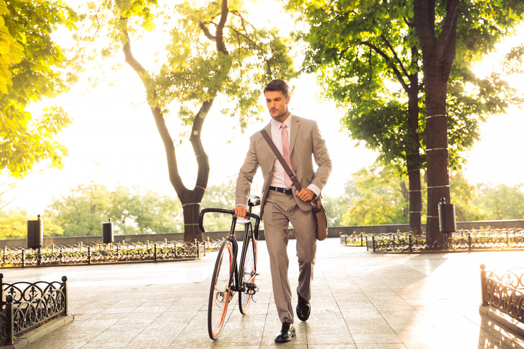 young businessman walking with bicycle on the street in town
