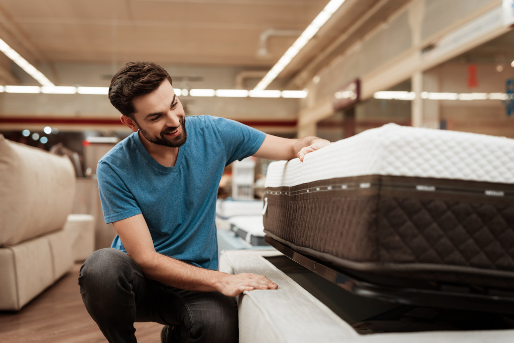 a man touching a bed shopping for furniture pieces