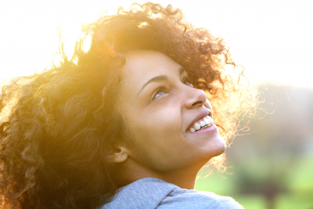 a curly-haired woman smiles while looking up