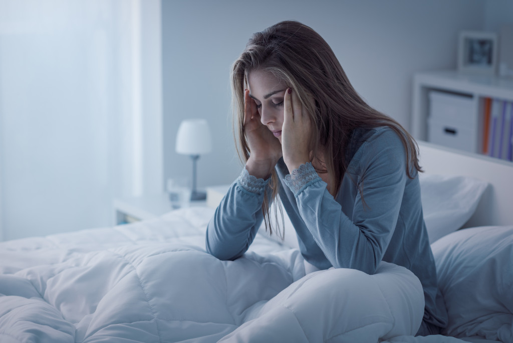 A woman who can't sleep massaging her temples while awake in bed