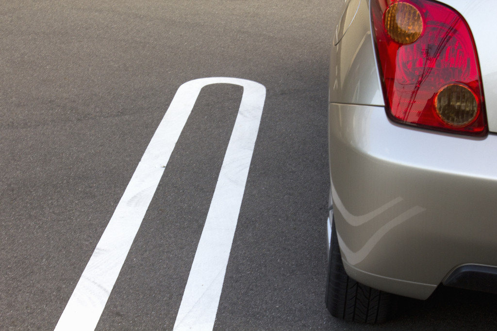 An asphalt parking lot with a white line and a parked car